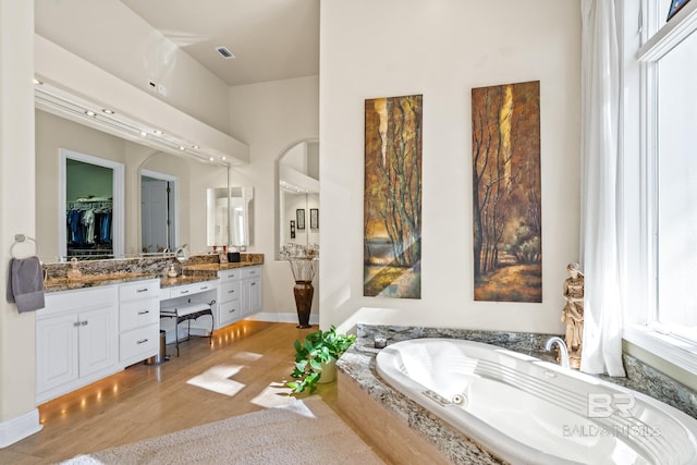 bathroom with vanity, wood-type flooring, and tiled bath