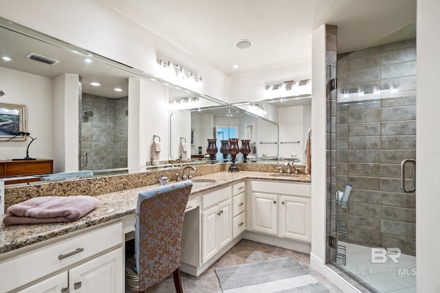 bathroom with a shower with door, vanity, and tile patterned flooring