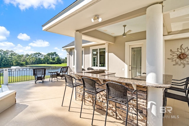 view of patio with ceiling fan and a water view