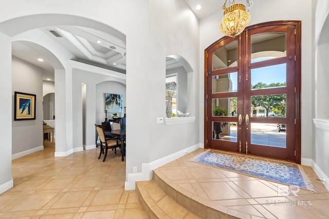 foyer entrance with coffered ceiling, a notable chandelier, beam ceiling, french doors, and a high ceiling