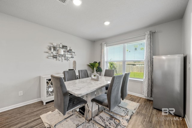 dining space with a textured ceiling and dark hardwood / wood-style floors