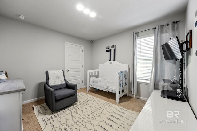 bedroom featuring light colored carpet and a nursery area