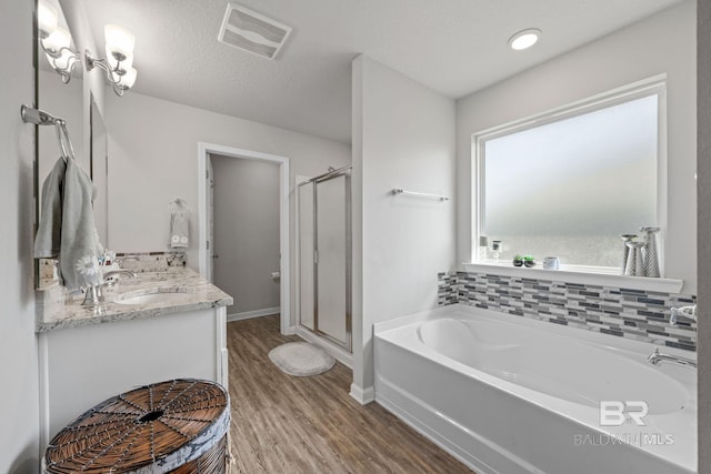 bathroom featuring a textured ceiling, hardwood / wood-style flooring, tasteful backsplash, separate shower and tub, and vanity