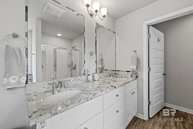 bathroom with vanity, a textured ceiling, an enclosed shower, and hardwood / wood-style flooring