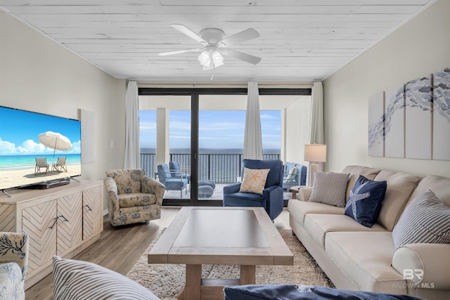 living room with ceiling fan, light hardwood / wood-style flooring, expansive windows, a water view, and wood ceiling