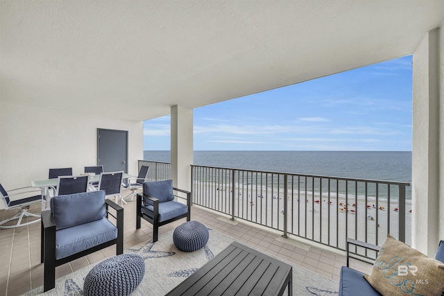 balcony featuring outdoor lounge area, a water view, and a view of the beach