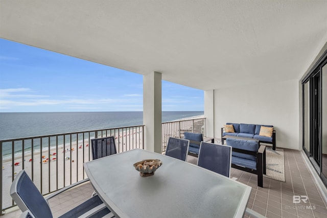 balcony featuring an outdoor hangout area, a water view, and a beach view