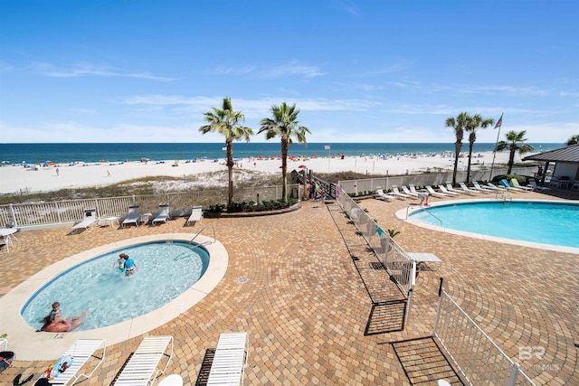 view of swimming pool featuring a view of the beach, a patio, and a water view