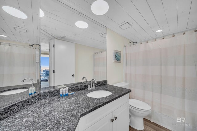 bathroom featuring wood-type flooring, vanity, and toilet