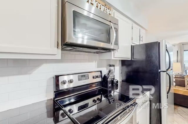 kitchen featuring backsplash, stainless steel appliances, white cabinetry, and light tile floors