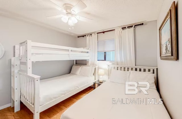 bedroom with wood-type flooring, ceiling fan, and a textured ceiling