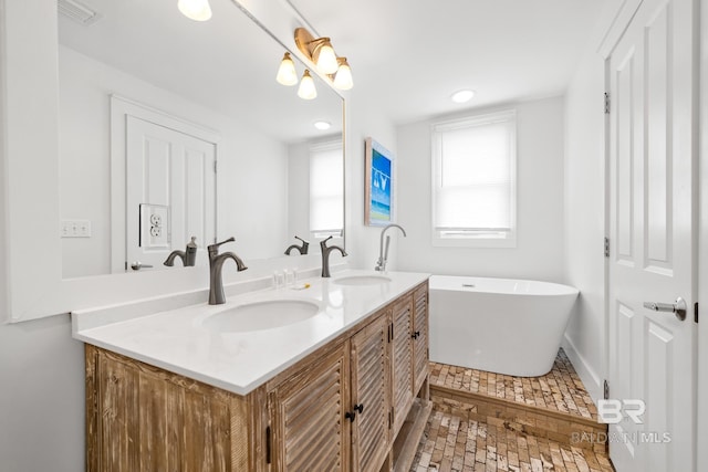full bathroom with double vanity, visible vents, a sink, and a soaking tub