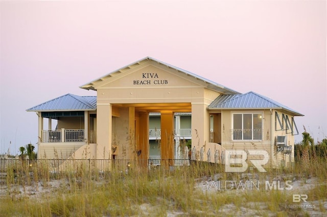 view of front of property featuring metal roof and fence