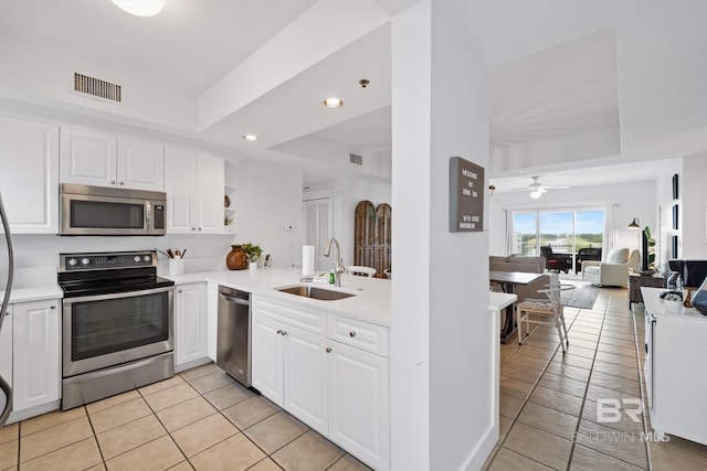 kitchen featuring a sink, open floor plan, appliances with stainless steel finishes, and a raised ceiling