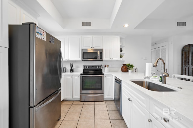 kitchen with a tray ceiling, light countertops, a sink, stainless steel appliances, and visible vents