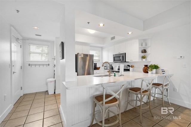 kitchen with a sink, visible vents, white cabinets, a peninsula, and appliances with stainless steel finishes