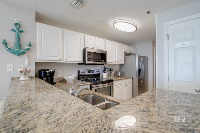 kitchen featuring white cabinets, sink, appliances with stainless steel finishes, and a textured ceiling