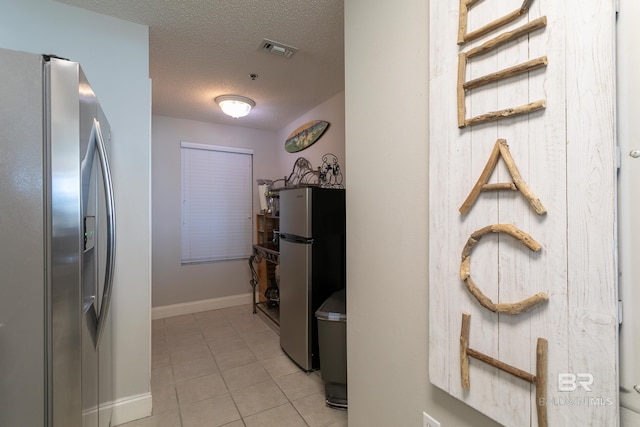 corridor featuring light tile patterned floors and a textured ceiling