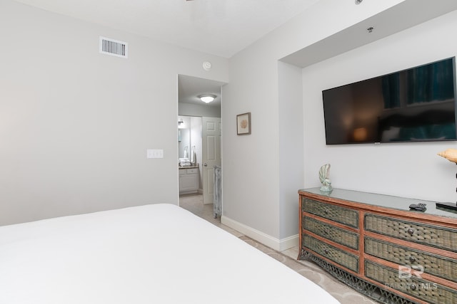 bedroom with ensuite bathroom and light tile patterned floors