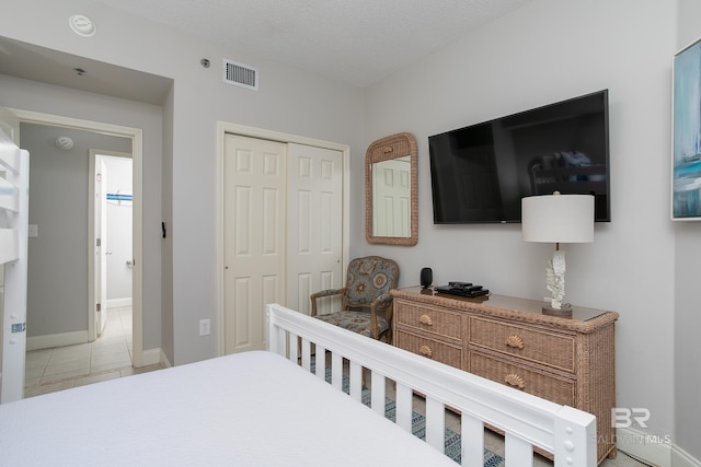 tiled bedroom featuring a textured ceiling and a closet