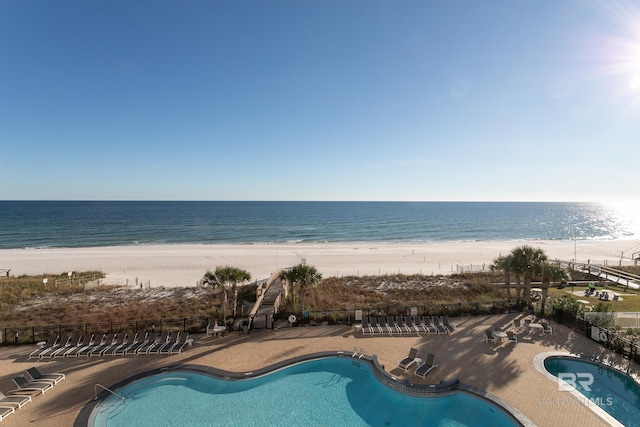 view of pool featuring a water view, a patio, and a view of the beach