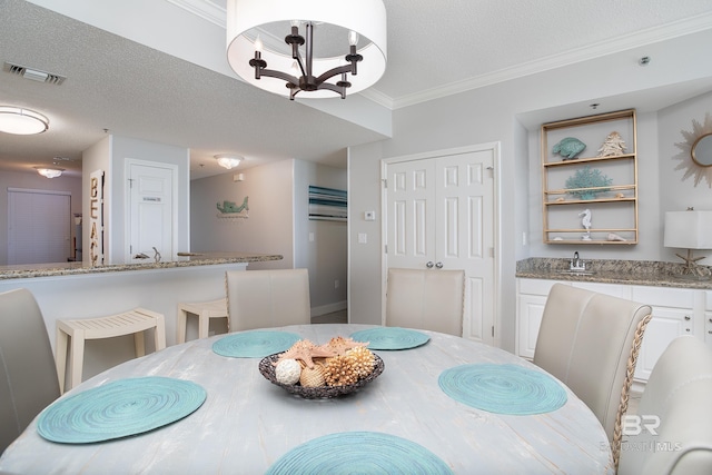 dining room with a chandelier, a textured ceiling, and ornamental molding