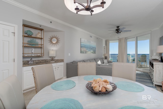 dining room featuring light tile patterned floors, ceiling fan with notable chandelier, ornamental molding, and sink