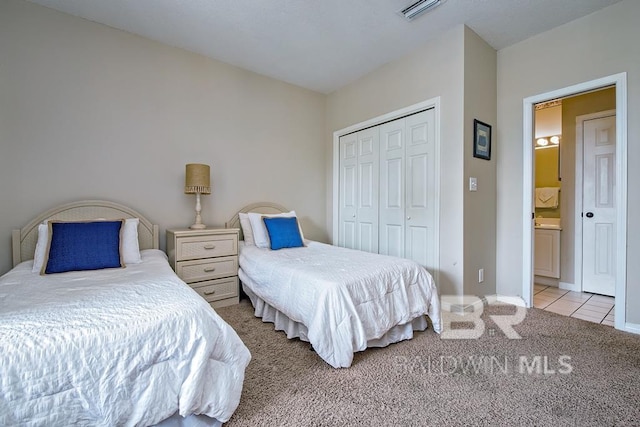 carpeted bedroom featuring a closet, tile patterned flooring, visible vents, and baseboards