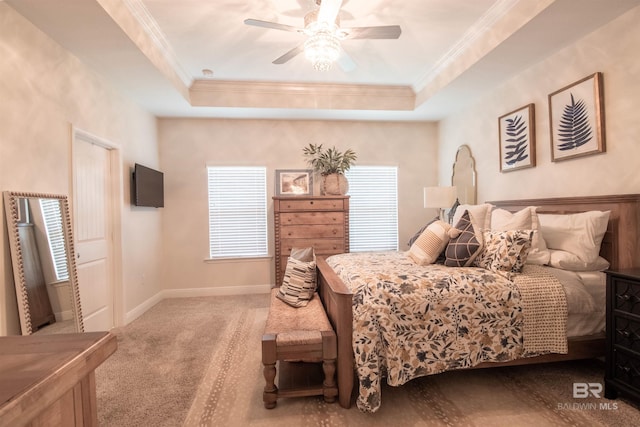 bedroom with crown molding, carpet flooring, a tray ceiling, baseboards, and a ceiling fan