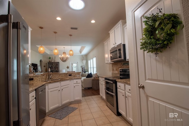 kitchen featuring stainless steel appliances, a sink, white cabinetry, visible vents, and a peninsula