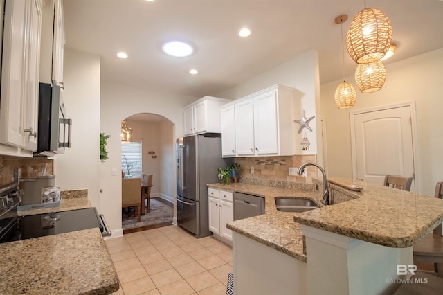 kitchen featuring light stone countertops, arched walkways, stainless steel appliances, white cabinets, and a peninsula