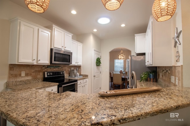 kitchen featuring recessed lighting, arched walkways, appliances with stainless steel finishes, and white cabinetry