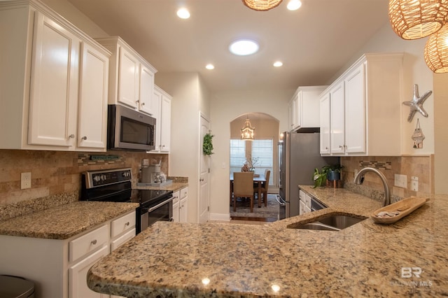 kitchen with appliances with stainless steel finishes, light stone countertops, arched walkways, and a sink
