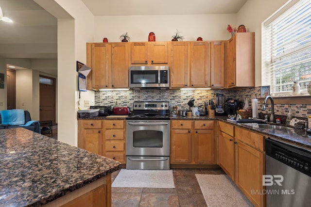 kitchen with dark stone counters, tasteful backsplash, sink, and stainless steel appliances