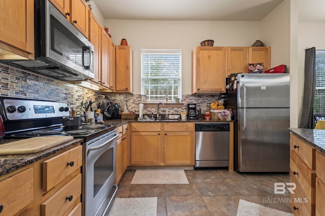 kitchen with dark stone countertops, tasteful backsplash, sink, and stainless steel appliances