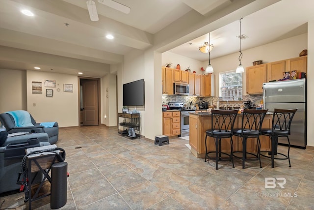 kitchen with a kitchen island, appliances with stainless steel finishes, hanging light fixtures, decorative backsplash, and a kitchen breakfast bar