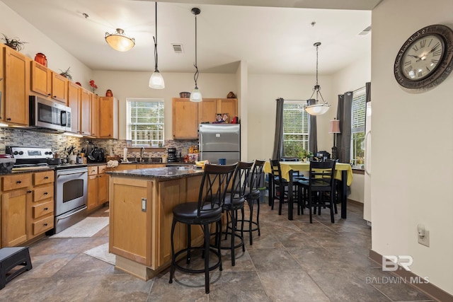 kitchen featuring stainless steel appliances, backsplash, decorative light fixtures, a breakfast bar area, and a center island