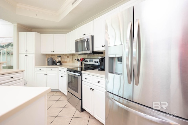 kitchen with tasteful backsplash, crown molding, white cabinetry, appliances with stainless steel finishes, and light tile patterned floors