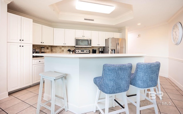 kitchen featuring a kitchen bar, appliances with stainless steel finishes, white cabinetry, and a center island with sink