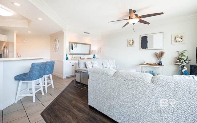 living room featuring ornamental molding, light tile patterned floors, and ceiling fan