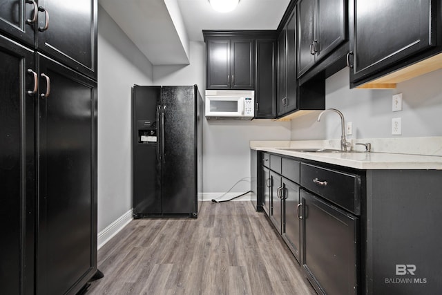 kitchen with sink, light wood-type flooring, and black fridge