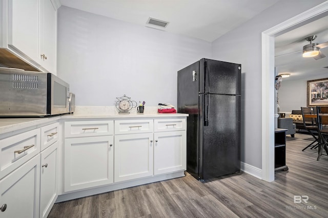 kitchen featuring white cabinetry, light hardwood / wood-style flooring, and black fridge