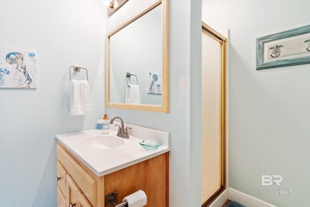 bathroom featuring a shower with door and vanity