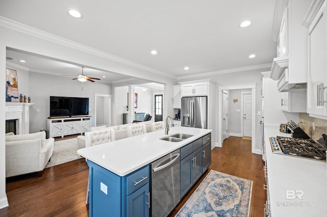 kitchen with appliances with stainless steel finishes, blue cabinets, an island with sink, sink, and white cabinets