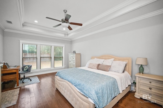 bedroom featuring a tray ceiling, dark wood-type flooring, ornamental molding, and ceiling fan