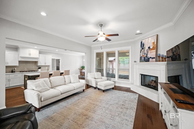 living room featuring dark wood-type flooring, ceiling fan, and crown molding