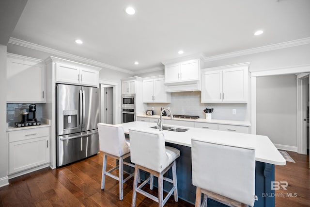 kitchen featuring appliances with stainless steel finishes, dark hardwood / wood-style floors, white cabinets, a kitchen bar, and a kitchen island with sink