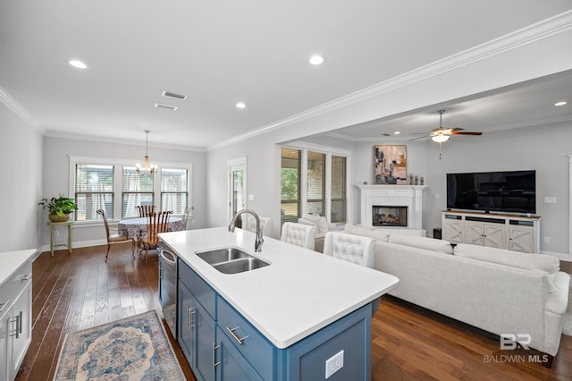 kitchen with blue cabinetry, sink, hanging light fixtures, dark hardwood / wood-style flooring, and a kitchen island with sink