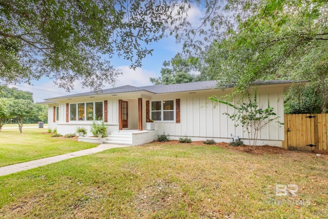 ranch-style house featuring a front yard, fence, board and batten siding, and roof with shingles