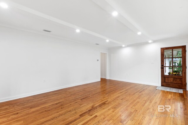 empty room featuring light hardwood / wood-style flooring and beam ceiling